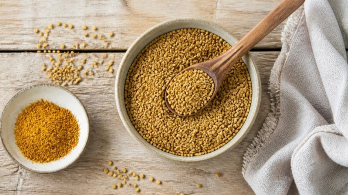 Gelbbraune Bockshornkleesamen in einer Schale mit Holzlöffel, daneben ein Schälchen Currymischung auf einem Holztisch